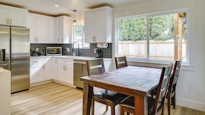 Una cocina moderna con armarios blancos, electrodomésticos de acero inoxidable y una mesa de comedor de madera.