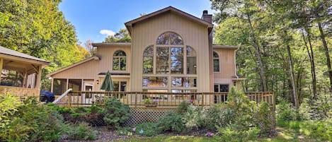A large, two-story house with a wrap-around porch, surrounded by lush greenery and trees.