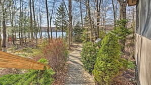 A wooden deck leading to a lake with trees and shrubs. - Pocono Lake Paradise w/ Private Beach & Dock! (Pocono Lake)