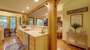 A kitchen with a large island, wooden cabinetry, and a 'welcome' sign.