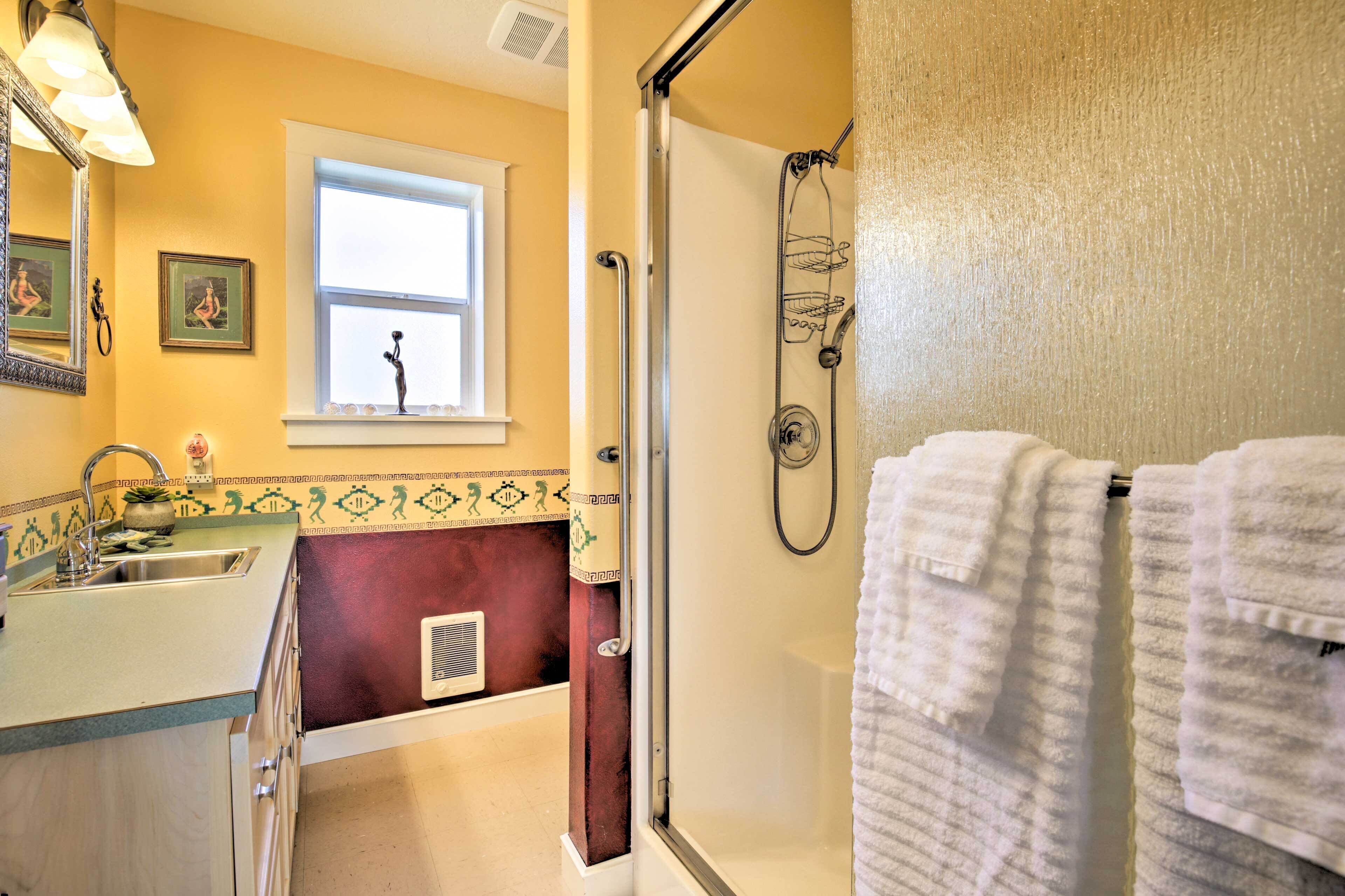 Une salle de bain avec une douche, un lavabo, une fenêtre et un porte-serviettes.