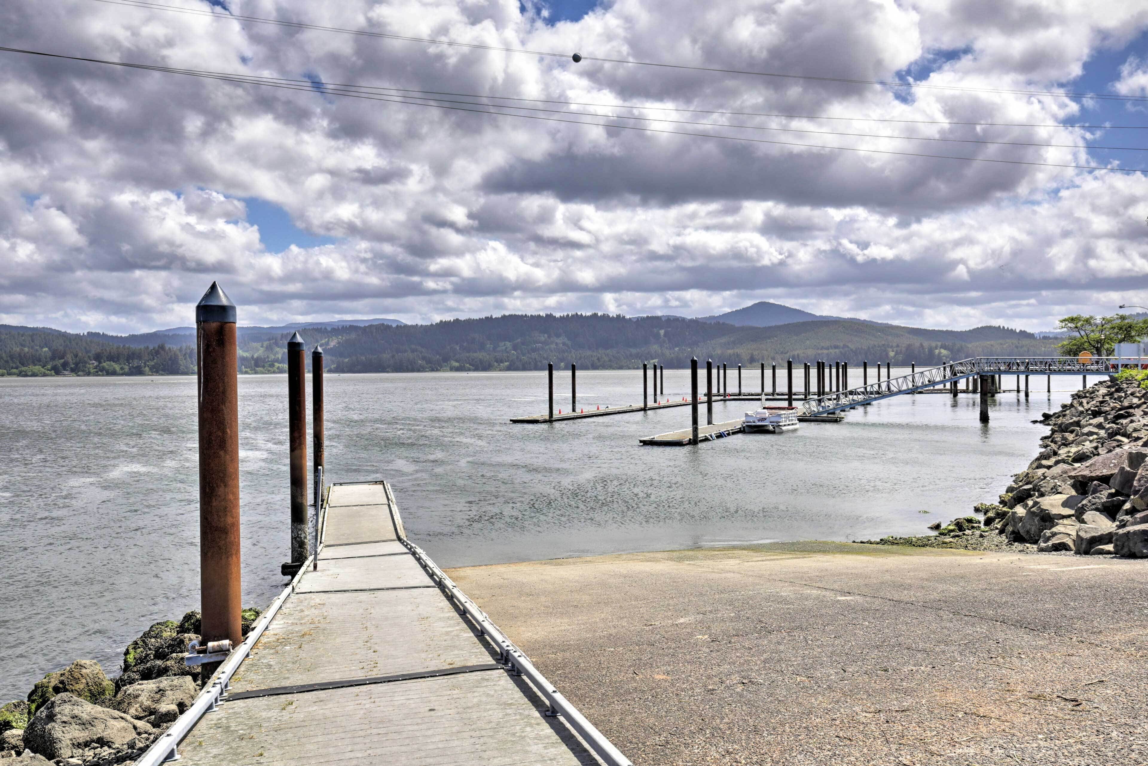 A wooden pier extending into a calm lake with boats docked at the end.