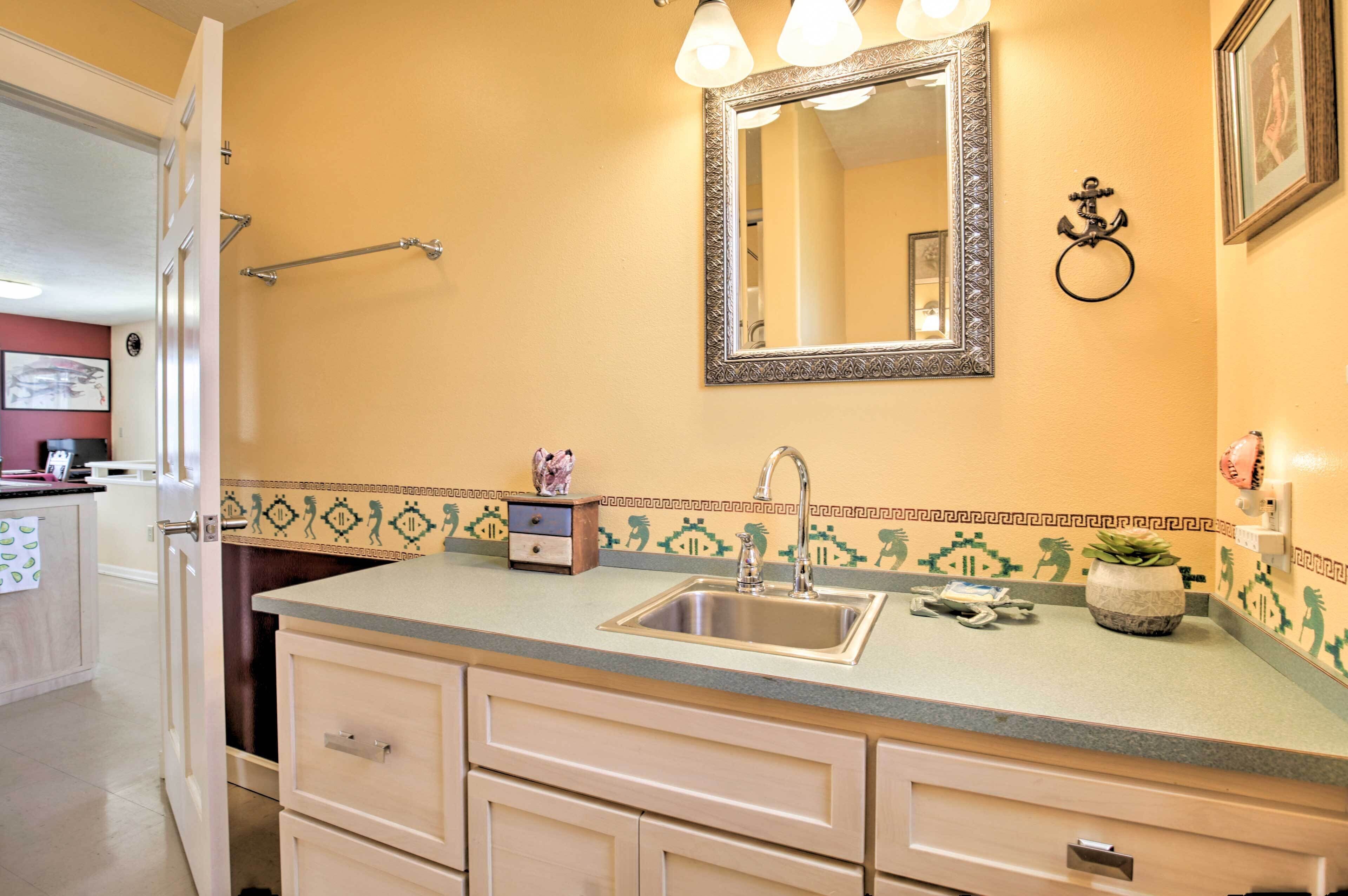 A bathroom with a sink, mirror, towel rack, and decorative tiles.