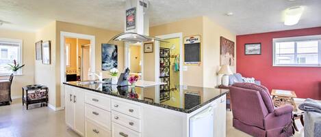 A spacious kitchen with white cabinets, a granite countertop, and a built-in oven.