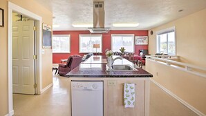 A compact kitchen with a dishwasher, a sink, and a window overlooking a dining area.