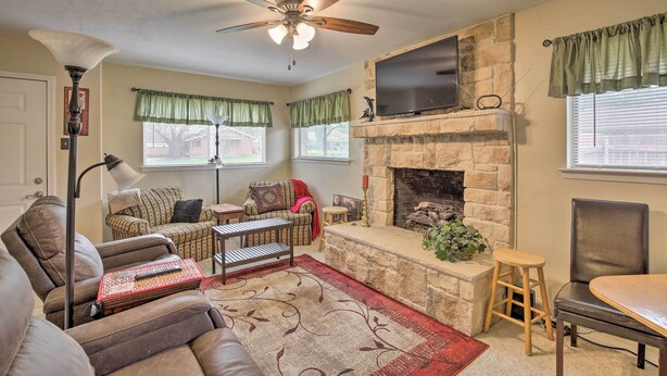 A living room with a fireplace, a ceiling fan, a television, and a sofa. - Home 1 Mi to University of Texas: Relax Fireside! (Richardson)