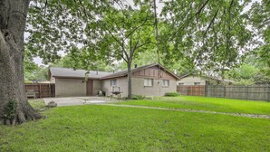 A residential house with a brick exterior, a front yard with a lawn, and a wooden fence. - Home 1 Mi to University of Texas: Relax Fireside! (Richardson)