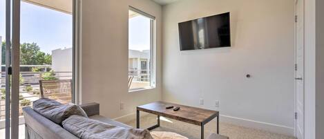 A modern living room with a sofa, a coffee table, and a TV mounted on the wall.