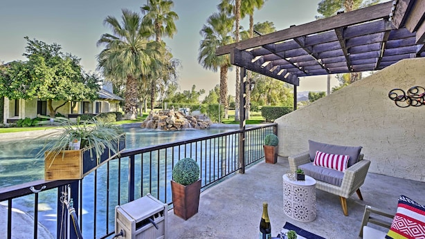 Un área junto a la piscina con una pérgola, sillas de descanso y vistas a la piscina y palmeras.