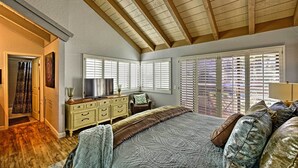 Un dormitorio con techo inclinado, una cama, un tocador, una silla y una ventana con persianas.