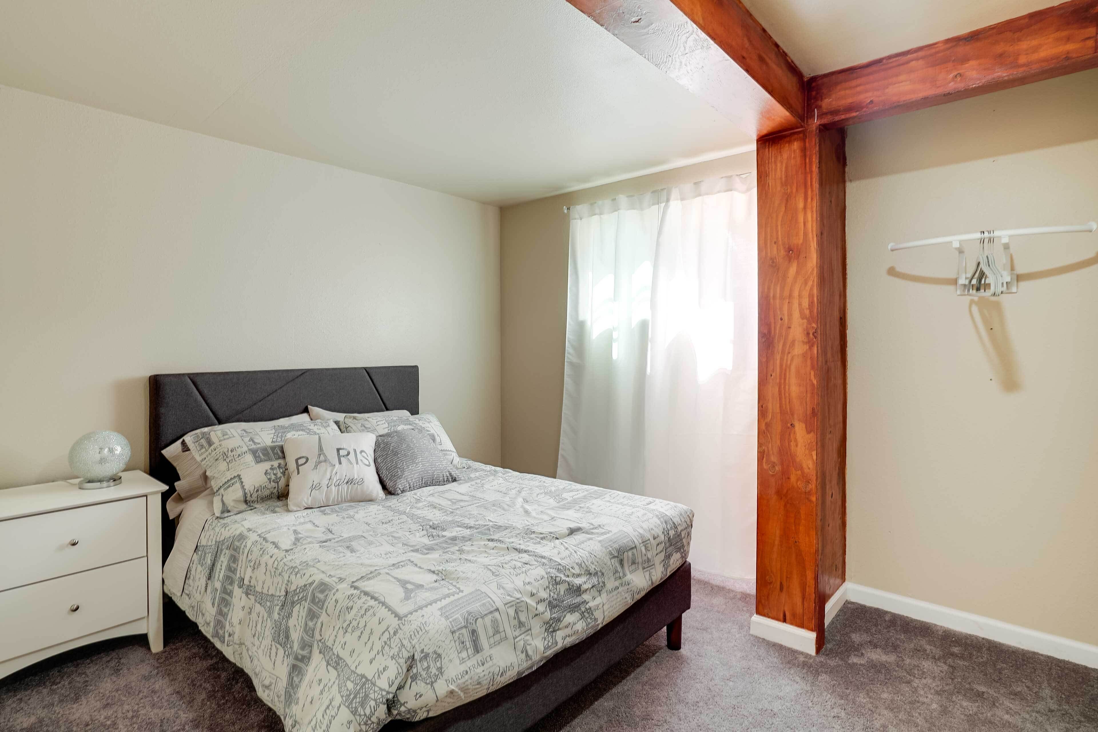 A bedroom with a bed, nightstand, and a wooden beam ceiling.