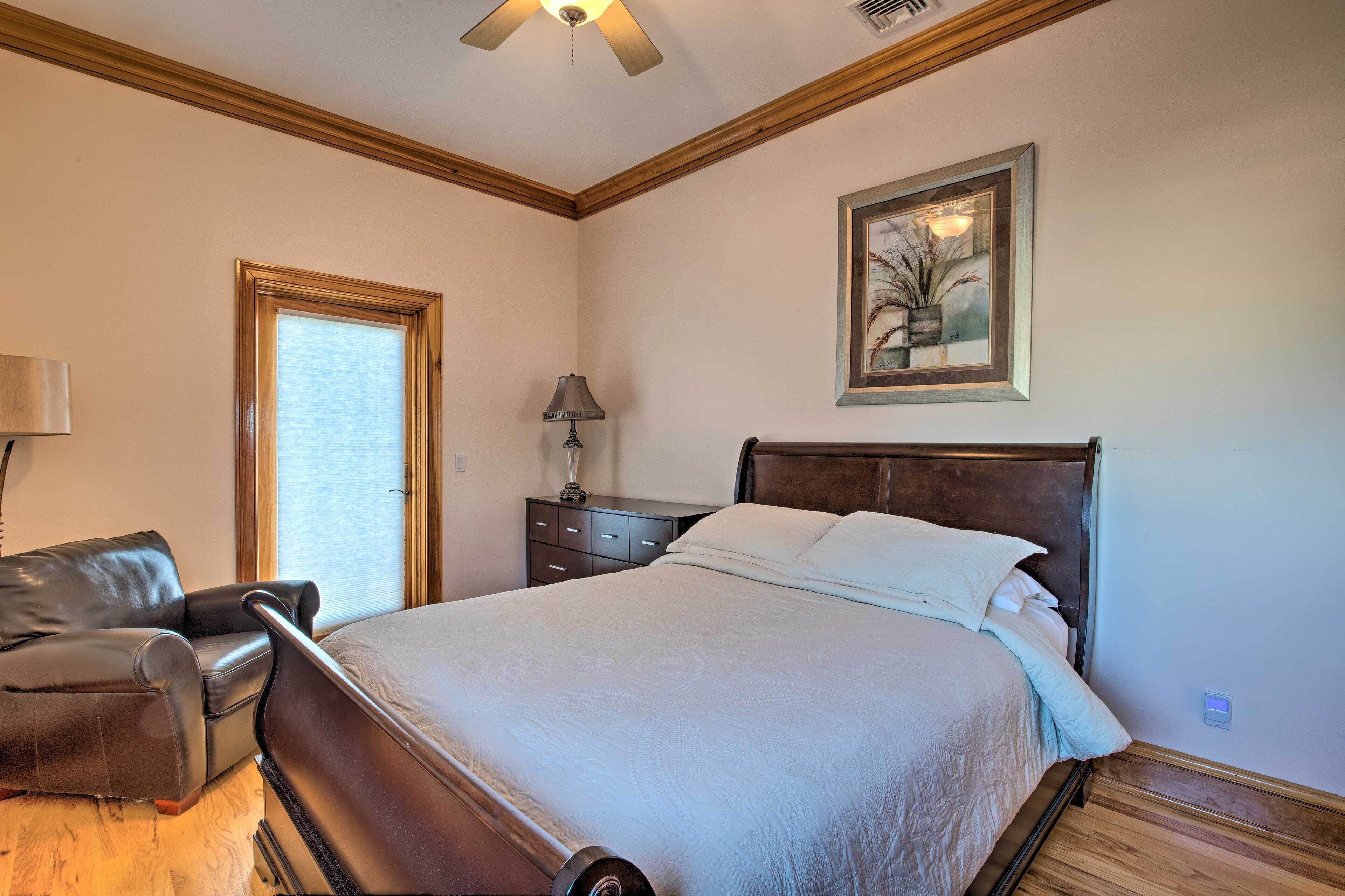 A bedroom with a bed, a chair, a nightstand, a lamp, and a framed picture on the wall.