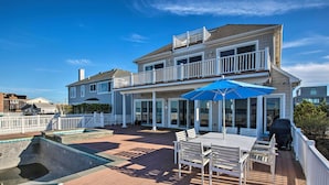A two-story house with a deck, outdoor seating, and a swimming pool. - Waterfront Home w/ Large Deck + Private Pool! (Westhampton Beach)