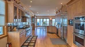 A spacious kitchen with wooden cabinets, stainless steel appliances, and a large island. - Waterfront Home w/ Large Deck + Private Pool! (Westhampton Beach)