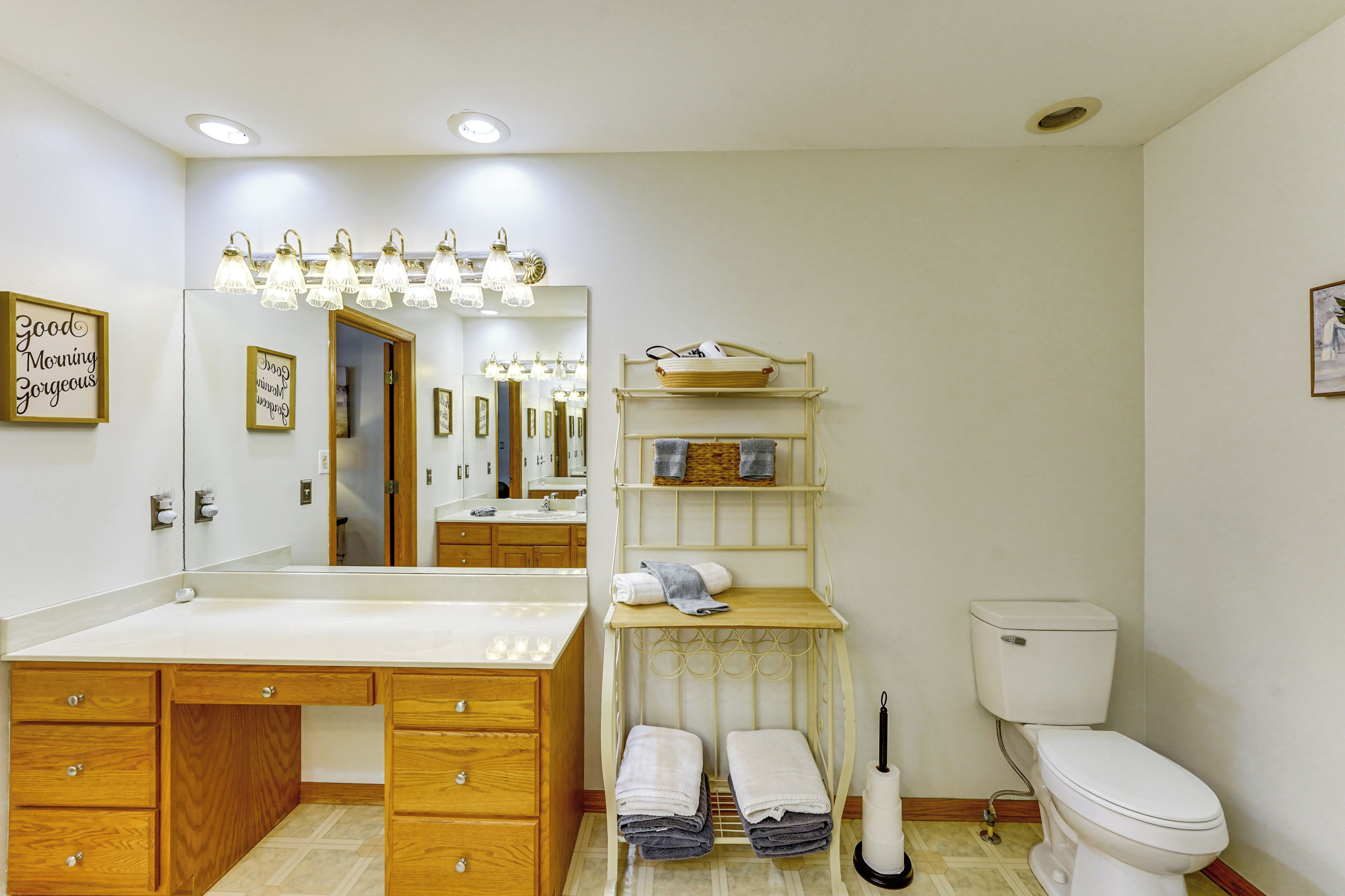 Een badkamer met een houten wastafelmeubel, toilet, wastafel en spiegel.