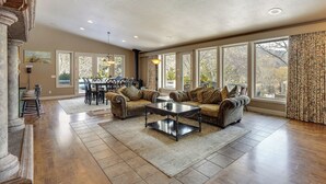 A spacious living room with a large window, a dining area, and a fireplace. - Hot Tub & Snake River Views at Twin Falls Home (Twin Falls)