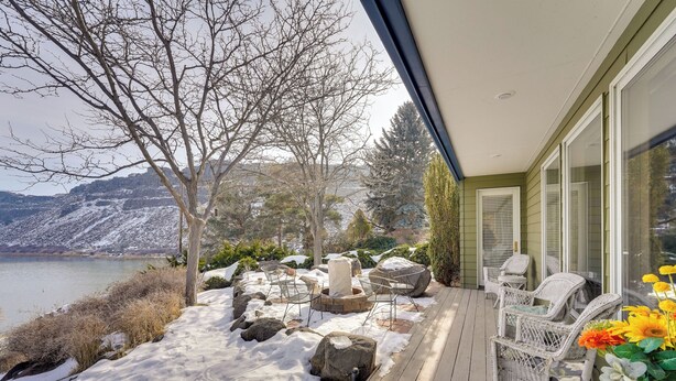 A wooden deck with outdoor furniture, a view of a lake, and snow-covered ground. - Hot Tub & Snake River Views at Twin Falls Home (Twin Falls)