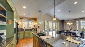 A kitchen with green cabinets, a dishwasher, a large island with a sink, and pendant lighting. - Hot Tub & Snake River Views at Twin Falls Home (Twin Falls)