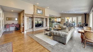 A spacious living room with a fireplace, a sofa, a coffee table, and a dining area with chairs. - Hot Tub & Snake River Views at Twin Falls Home (Twin Falls)