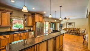 A spacious kitchen with wooden cabinets, granite countertops, and pendant lighting. - Tryon House w/ Hot Tub - Near Equestrian Centers! (Tryon)