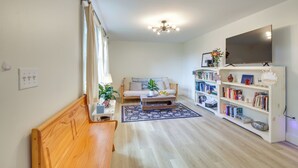 A living room with a wooden bench, a sofa, a coffee table, a bookshelf, and a TV. - Woodsy Pittston Retreat Near Kennebec River! (Gardiner)