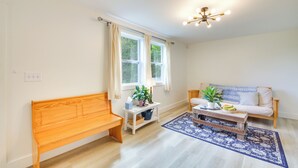 A living room with a wooden bench, a white sofa, a coffee table, and a blue patterned rug. - Woodsy Pittston Retreat Near Kennebec River! (Gardiner)
