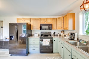 A modern kitchen with wooden cabinets, stainless steel appliances, and a window providing natural light.