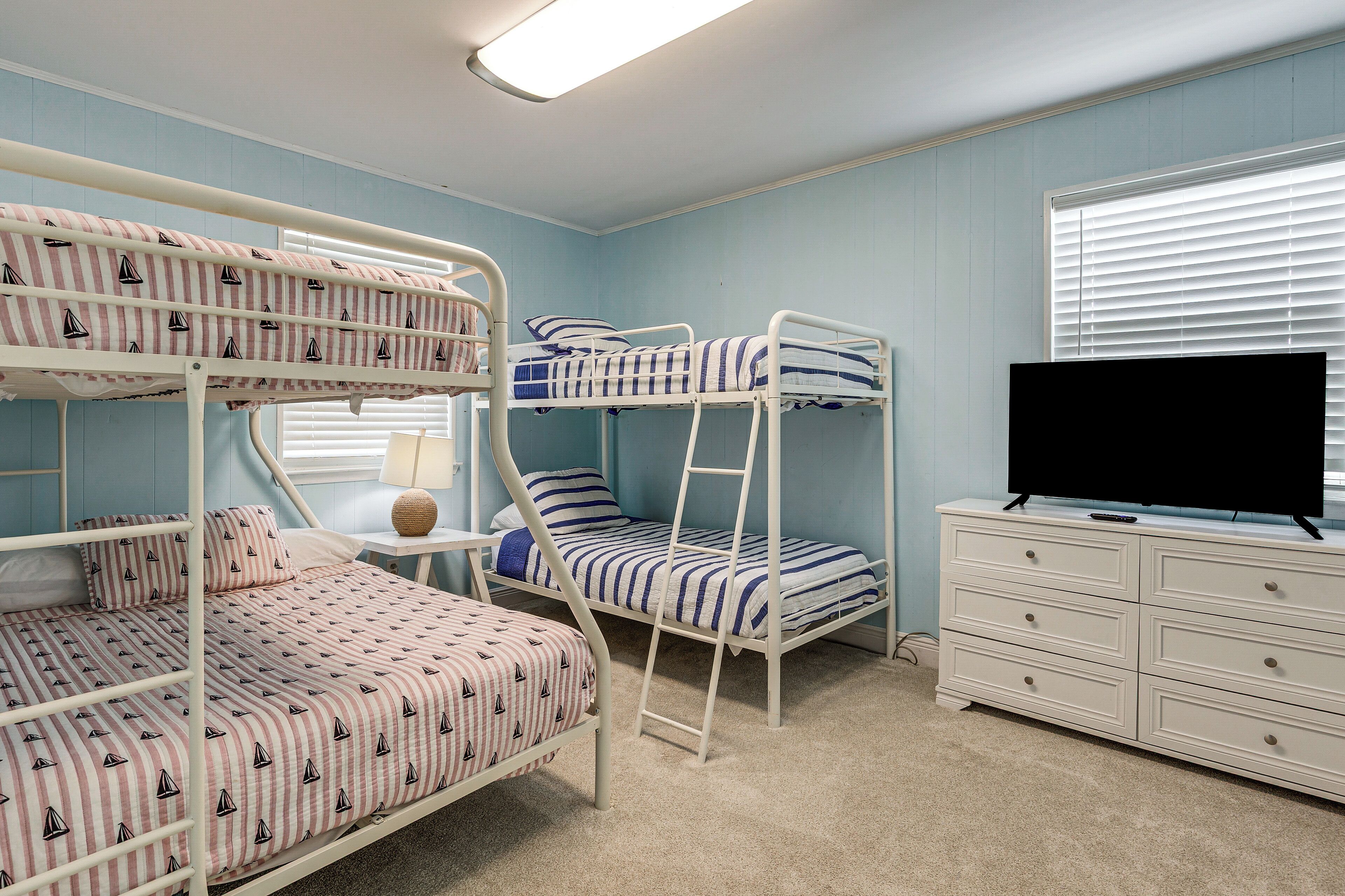 Een slaapkamer met een stapelbed, een televisie en een dressoir.