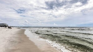 Uma praia com ondas, um edifício e um céu nublado.
