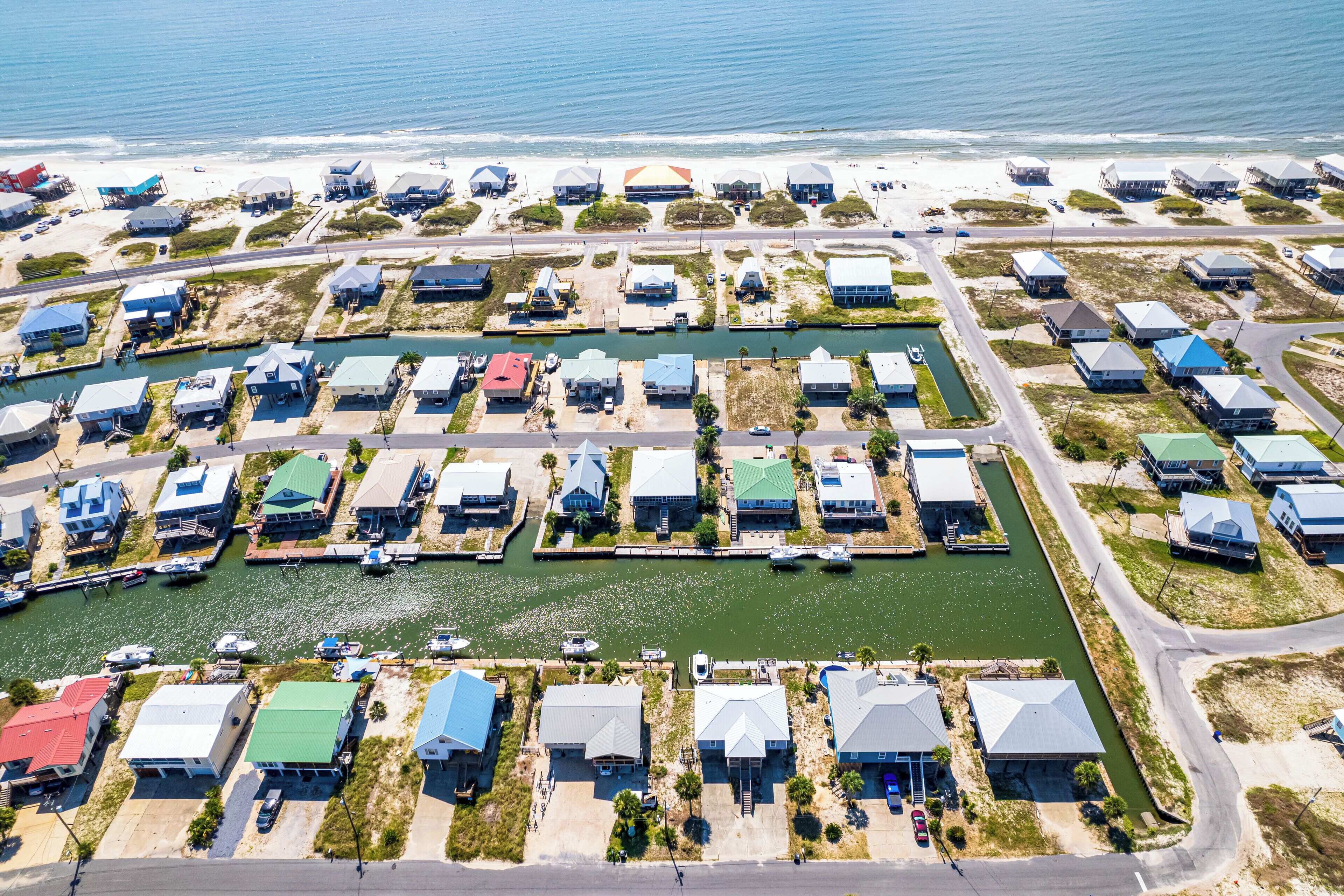 Vista aérea de una zona residencial costera, con casas alineadas en filas a lo largo de un canal estrecho, conectado por carreteras.