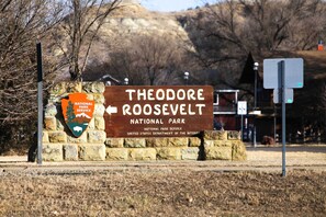 A sign for Theodore Roosevelt National Park with a directional arrow. - Roosevelt Suite of Dakota Place Lodge in Medora! (Medora)