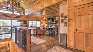 A spacious wooden cabin with a dining area, kitchen, and a large wooden door.