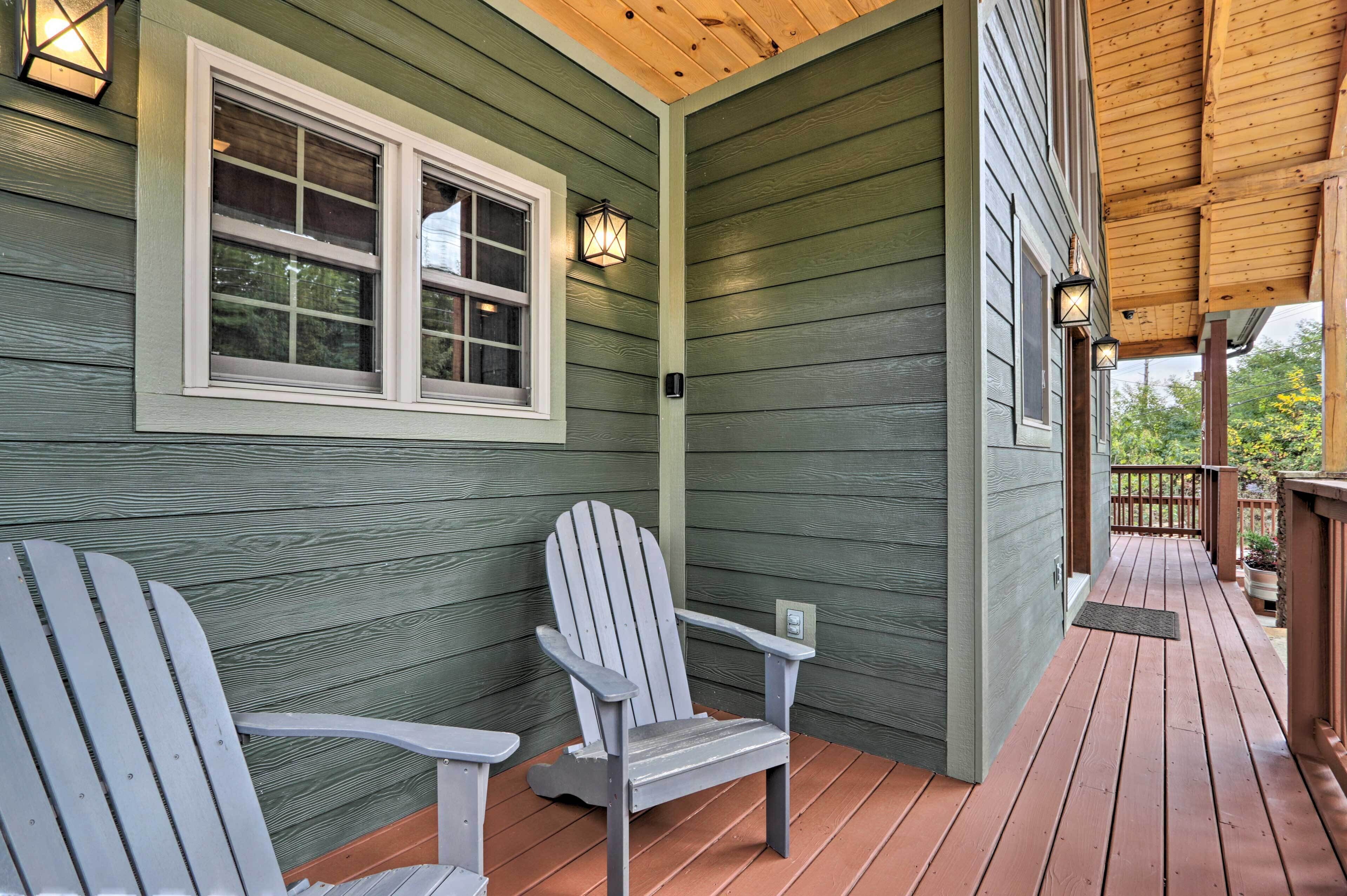 A wooden deck with two Adirondack chairs, a window with a white frame, and a porch railing.