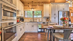 A spacious kitchen with white cabinetry, stainless steel appliances, and a wooden ceiling.