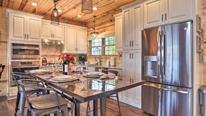 A modern kitchen with white cabinets, stainless steel appliances, and a central island with bar stools.