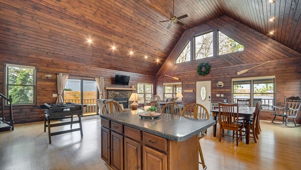 Una cocina amplia con una isla grande, techo de madera y ventanas panorámicas.