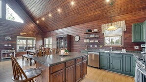 Una cocina amplia con armarios de madera, una isla central y una zona de comedor con sillas.