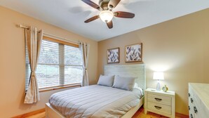 A bedroom with a bed, a nightstand, a dresser, a ceiling fan, and two framed pictures on the wall. - Waynesville Cabin Rental w/ Mountain Views (Waynesville)