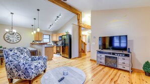 A spacious living area with a round table, a sofa, a TV, and a kitchen in the background. - Waynesville Cabin Rental w/ Mountain Views (Waynesville)