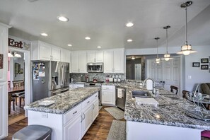 A modern kitchen with white cabinets, granite countertops, stainless steel appliances, and pendant lighting. - Welcoming Tehachapi Home w/ Deck & Grill! (Tehachapi)