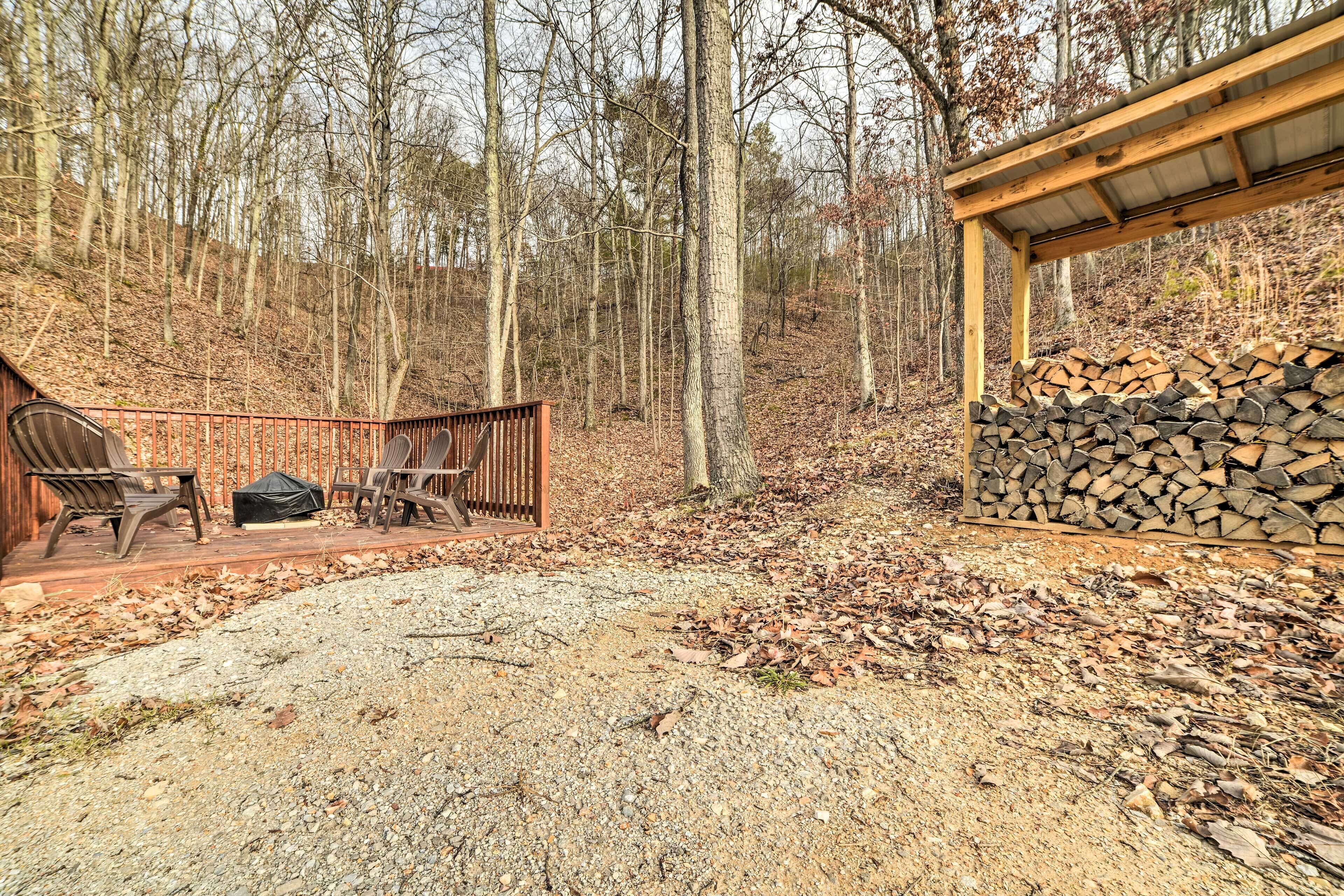 A wooden deck with chairs and a table, surrounded by a forest.