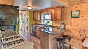 A kitchen with wooden cabinets, a granite countertop, a gas stove, a sink, and a window with a view. - Waterfront Syracuse Home: Deck, Fire Pit & Kayaks (Syracuse)