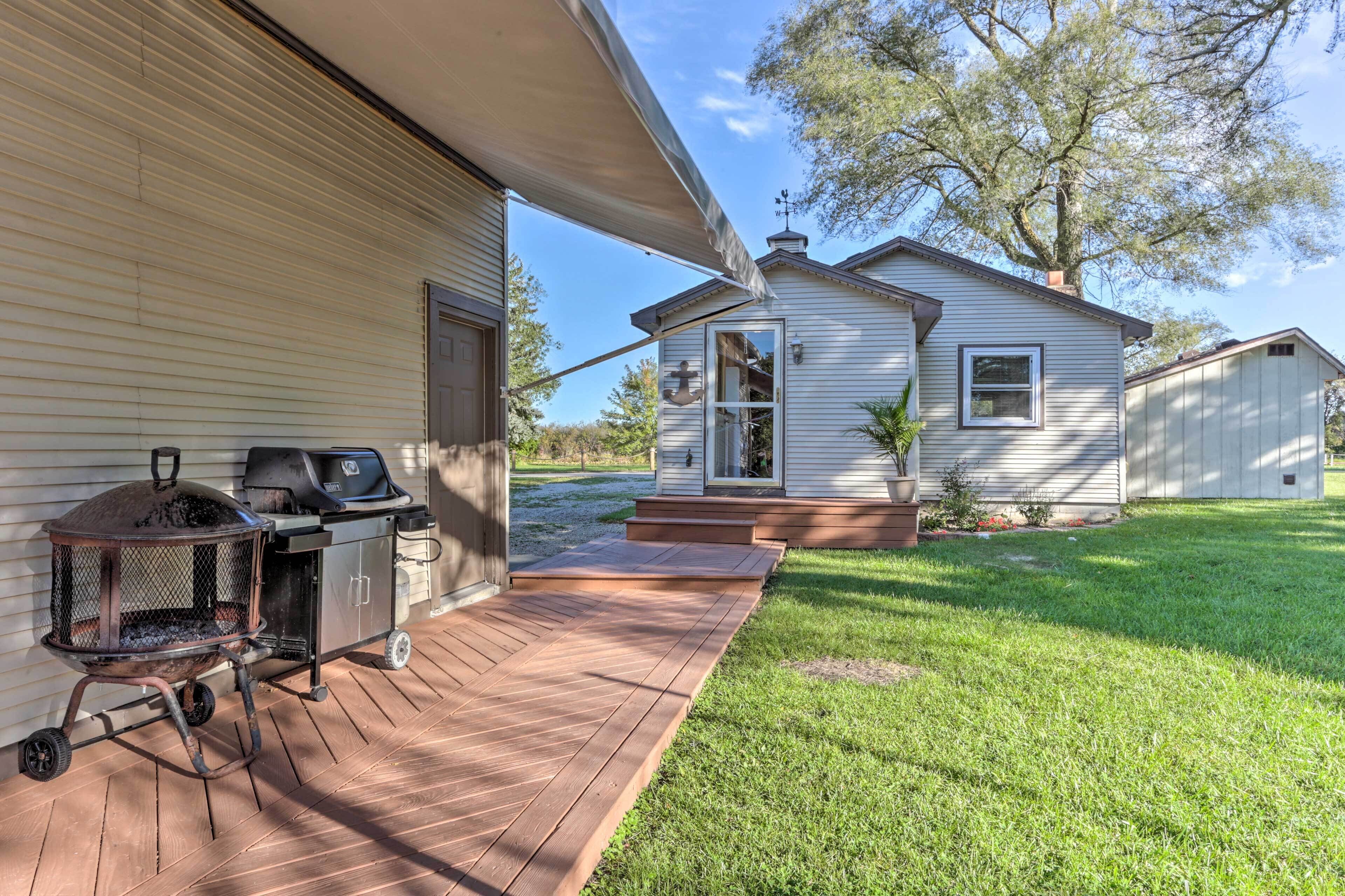A wooden deck leading to a house with a barbecue grill and a covered grill area.