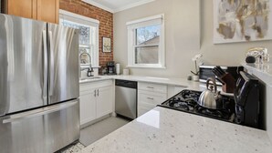 A modern kitchen with stainless steel appliances, white cabinetry, and a granite countertop. - Chic, Luxurious Sunnyside Home (Denver)
