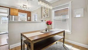 A modern kitchen with a wooden table, a vase of flowers, and a hanging light fixture. - Chic, Luxurious Sunnyside Home (Denver)