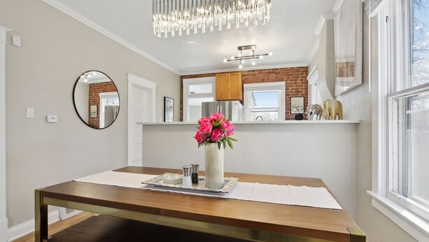 A dining area with a wooden table, a vase with flowers, and a chandelier. - Chic, Luxurious Sunnyside Home (Denver)