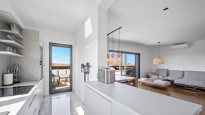 Una cucina moderna con una grande isola, un'area pranzo con un divano e vista sull'esterno.