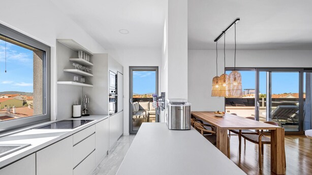 Una cucina moderna con una grande isola, elettrodomestici integrati e un'area pranzo con vista.