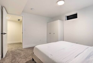 A bedroom with a bed, a wardrobe, and a door leading to another room. - Bright & Modern Arvada Home w/ Yard & Patio (Westminster)