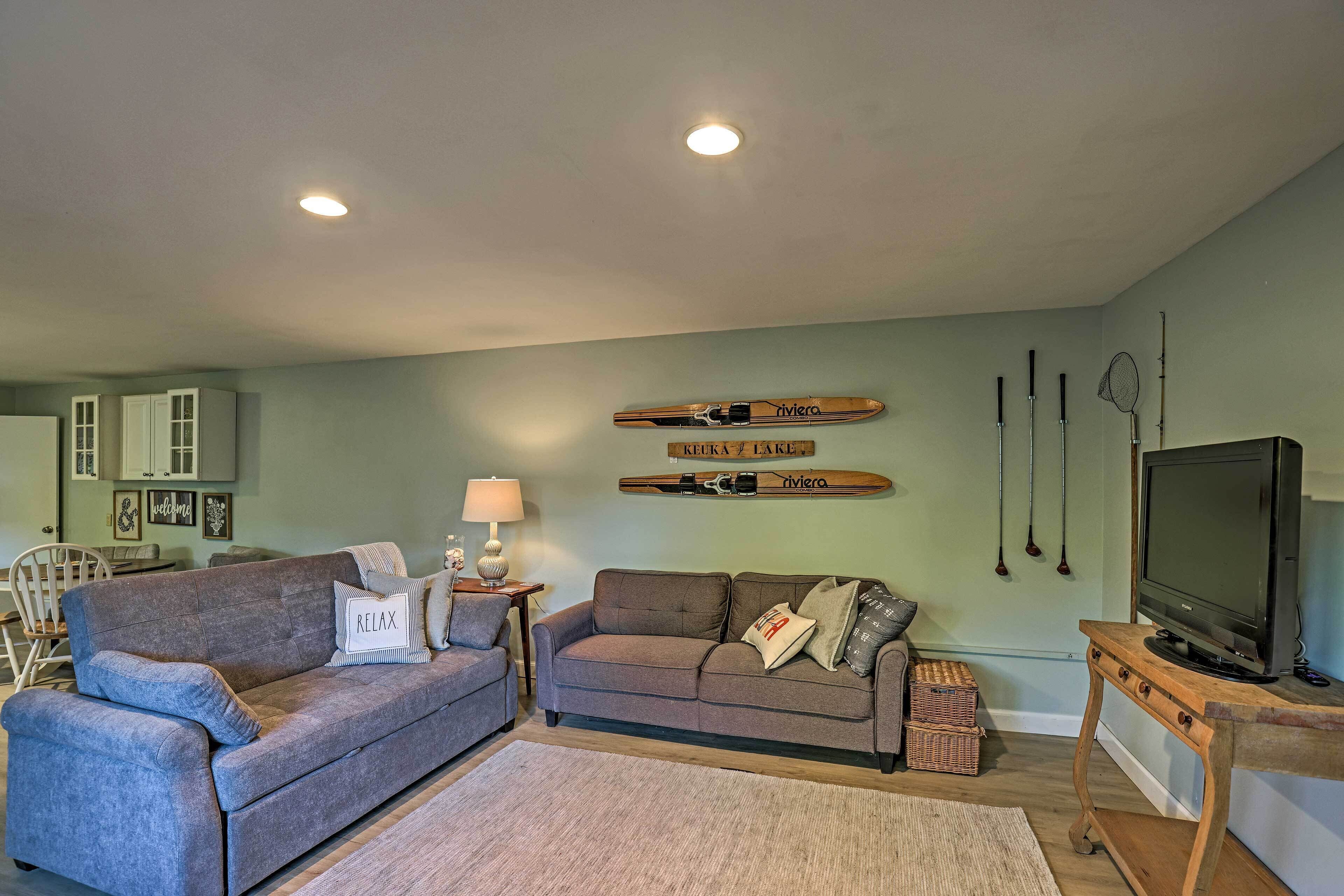 A living room with a grey sofa, a TV stand, and a wall-mounted TV.